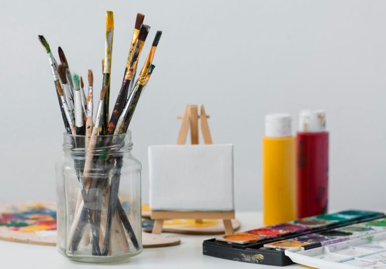 People participating in a canvas painting workshop, holding brushes and painting on canvases in a bright, creative studio environment